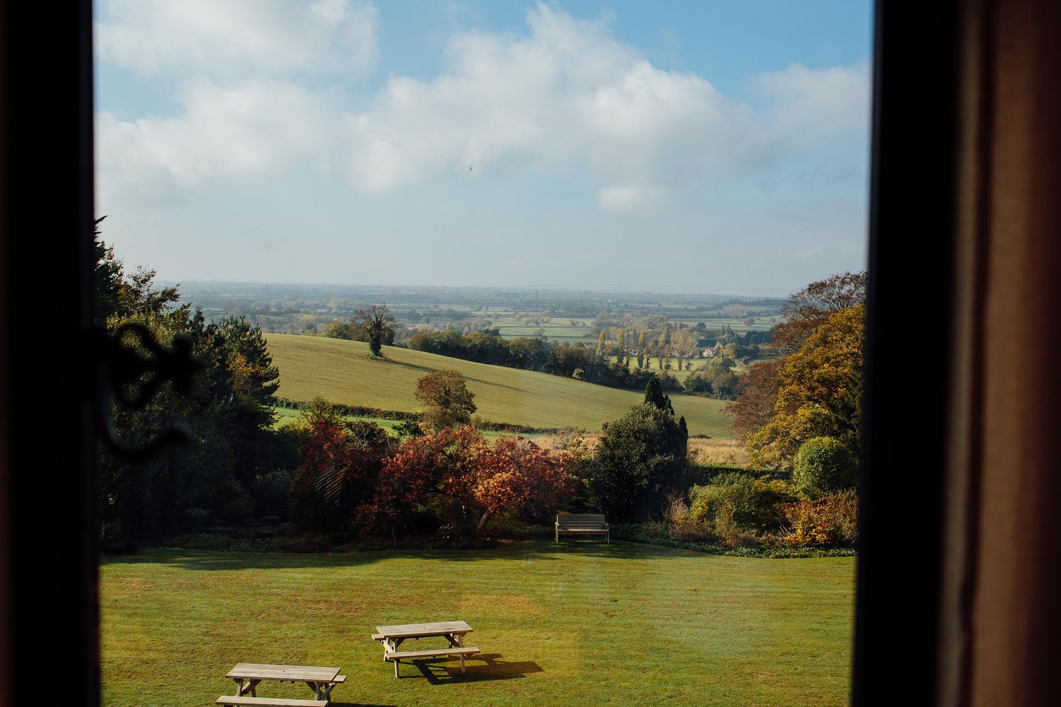 Rolling green hills and countryside landscape with picnic tables on a sunny autumn day.