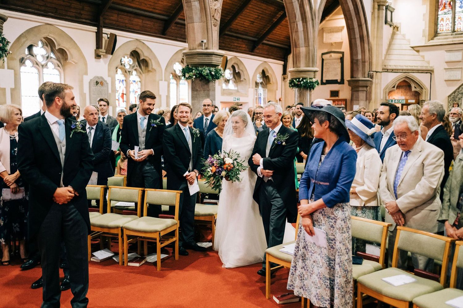 Wedding ceremony in progress inside a traditional church with wooden pews and stone architecture.