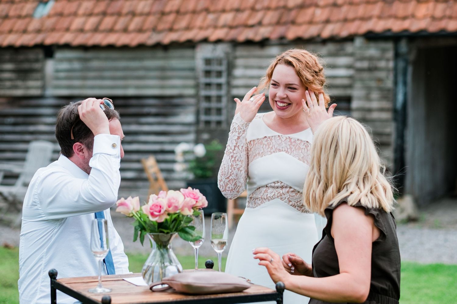 Wedding reception guests enjoying a casual outdoor meal at wooden tables.