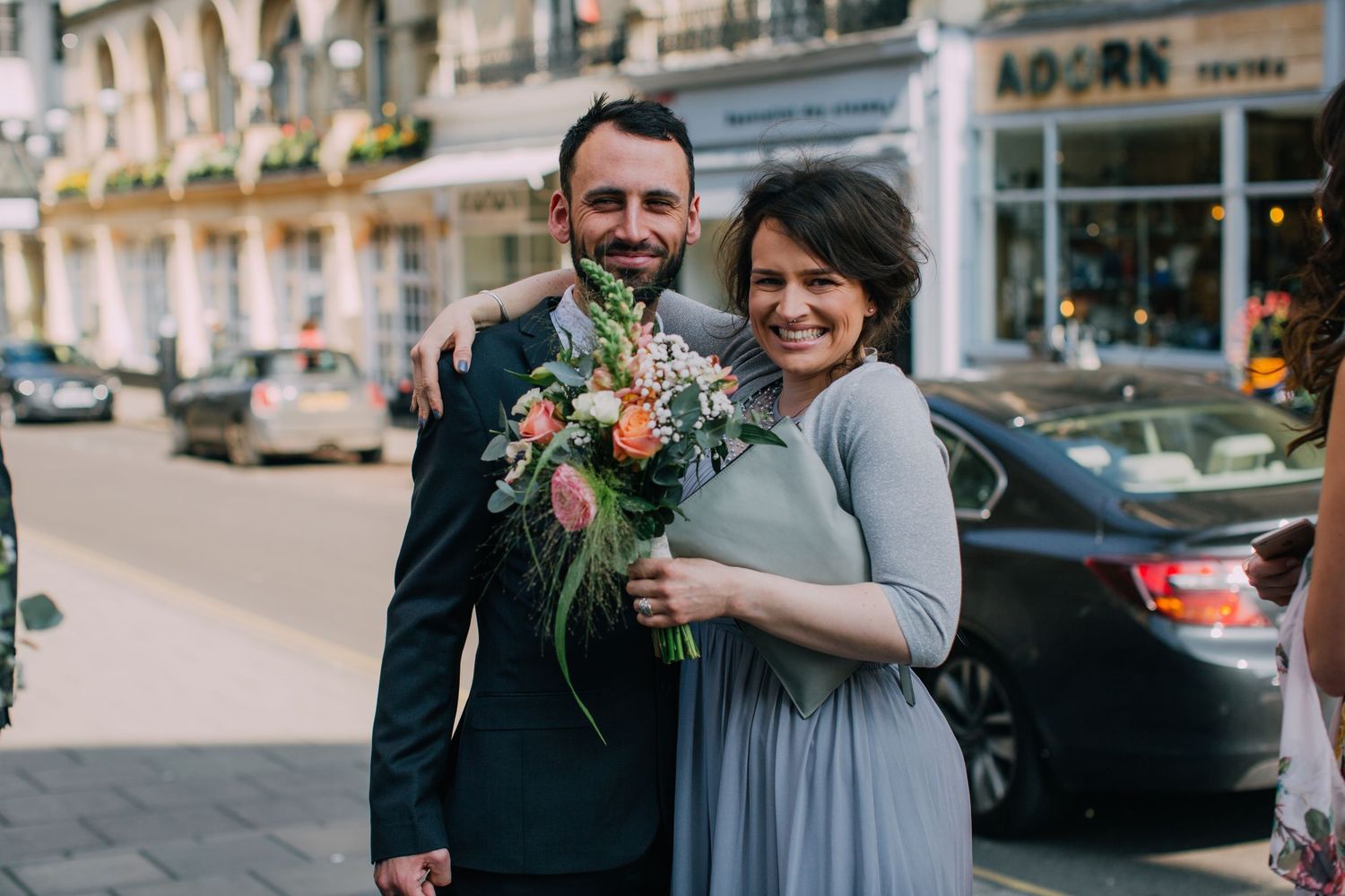 Wedding couple embracing on a European city street with historic architecture in the background.