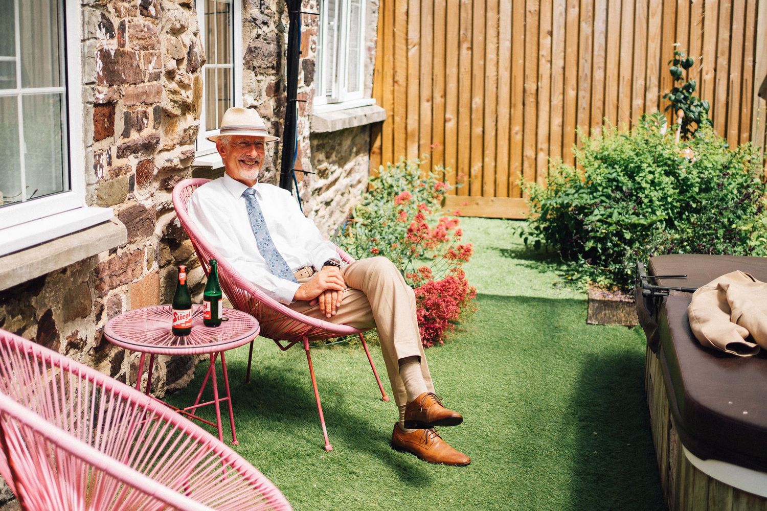 Person relaxing in garden chair wearing summer hat and light colored clothing.