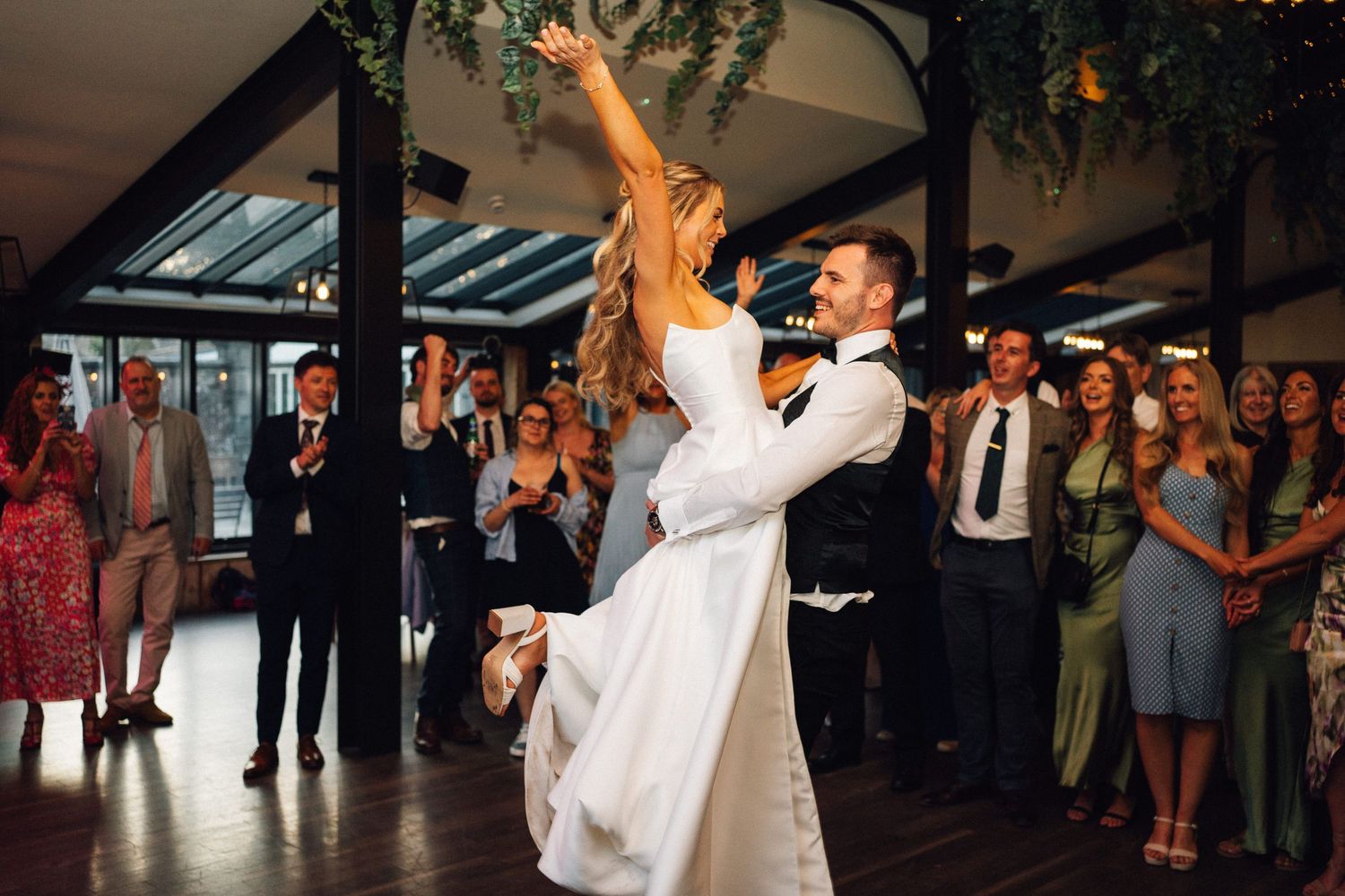 Couple shares an intimate dance moment under circular pendant lights at their wedding reception.