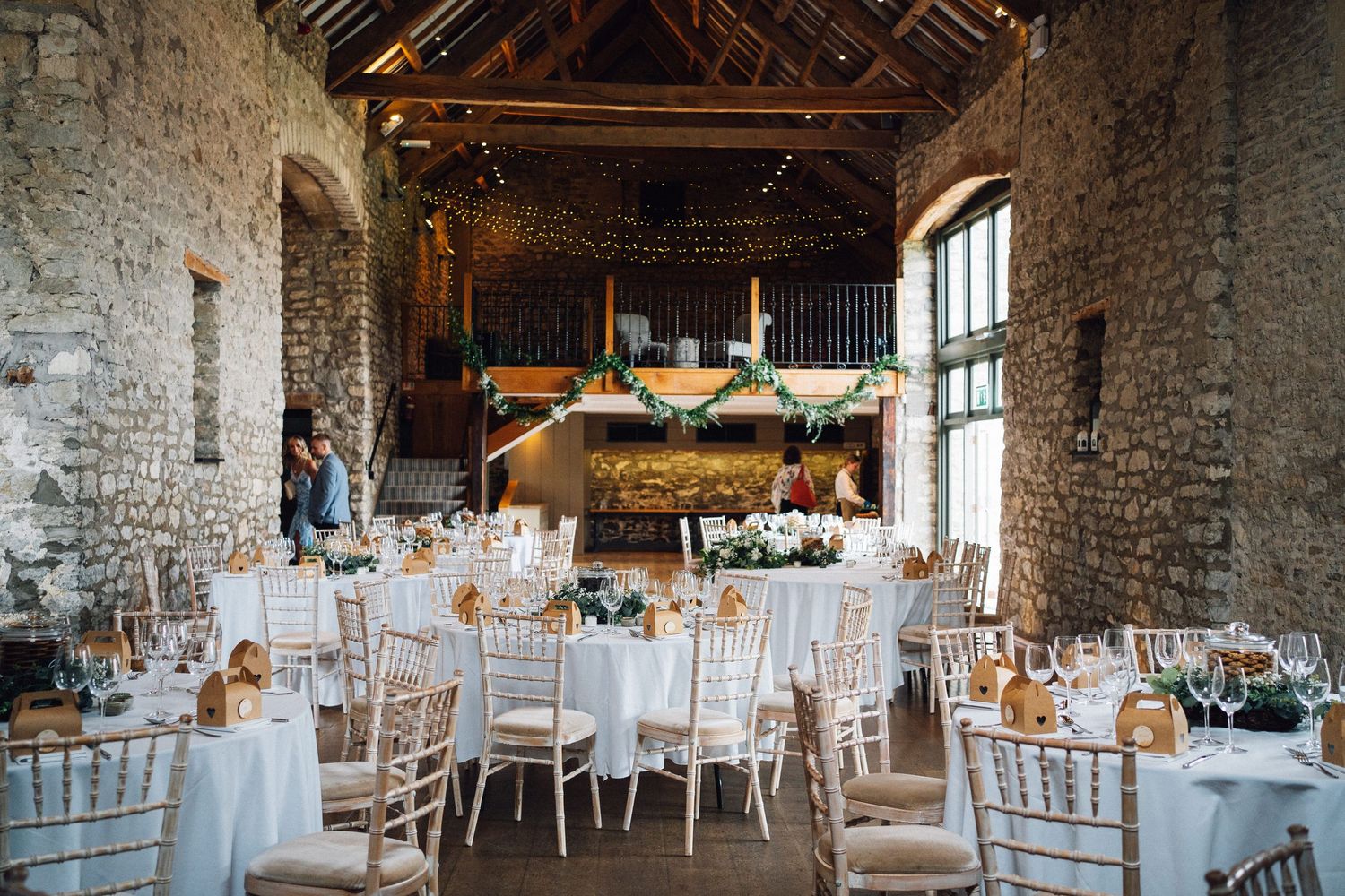 Rustic barn wedding reception venue with exposed stone walls and elegant table settings for a romantic celebration.