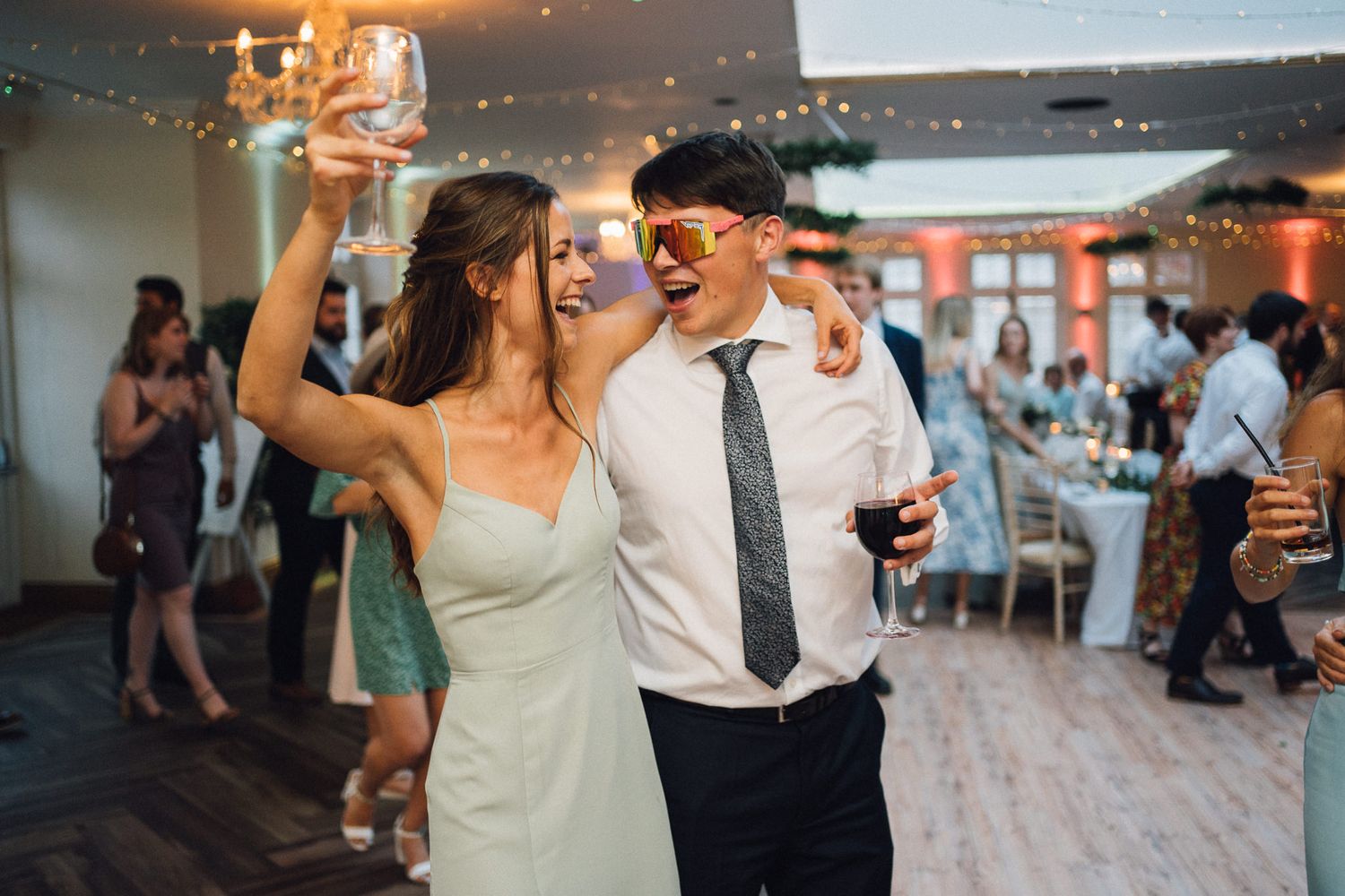 A couple dances together at their wedding reception under ambient lighting.