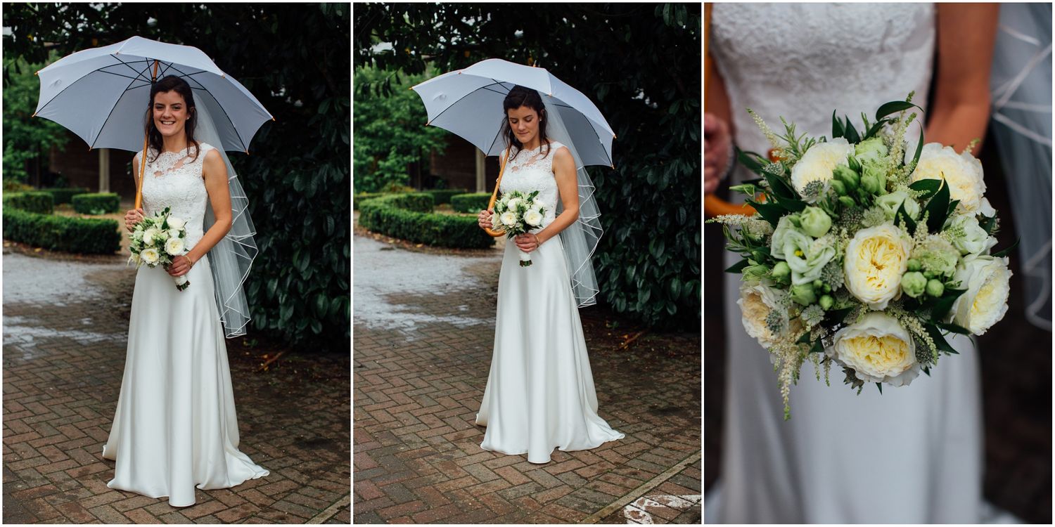 Bride holding white umbrella and bouquet during outdoor rainy wedding.