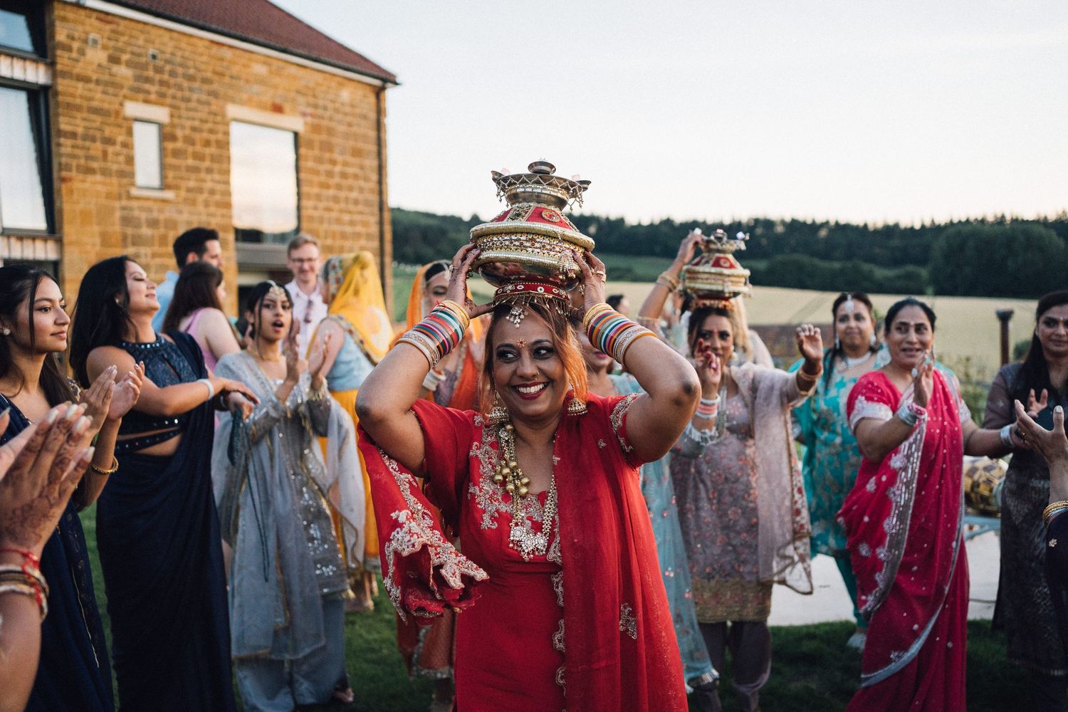 Wedding guests celebrate and dance together during an outdoor evening reception at a rustic venue.