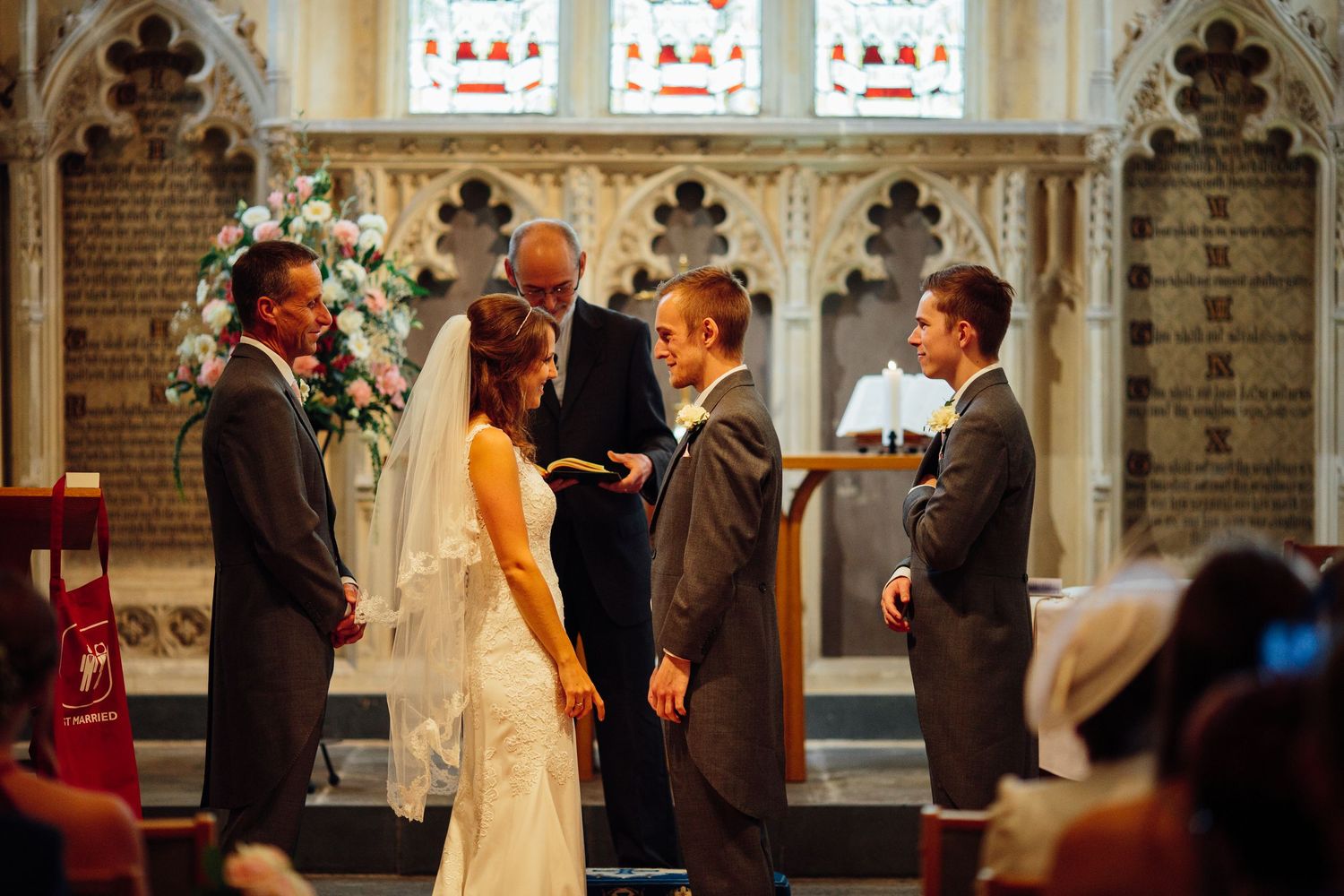 A collage of wedding ceremony moments showing decorative church windows and guests gathered in a stone chapel.