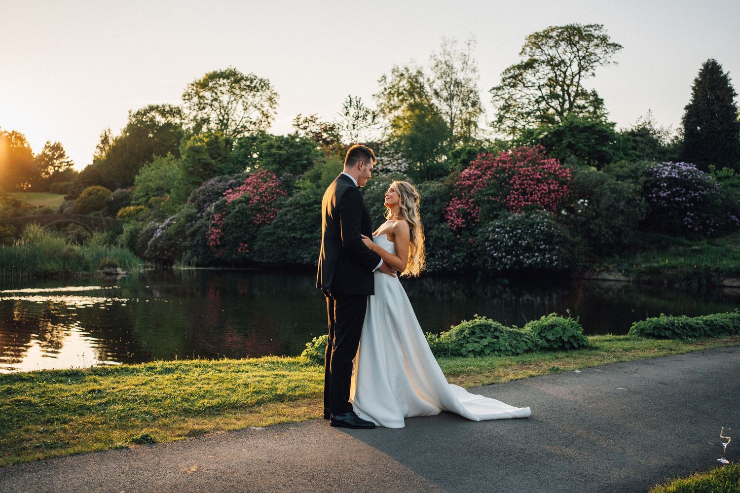 Romantic sunset wedding portraits captured along a lakeside path with natural golden light.