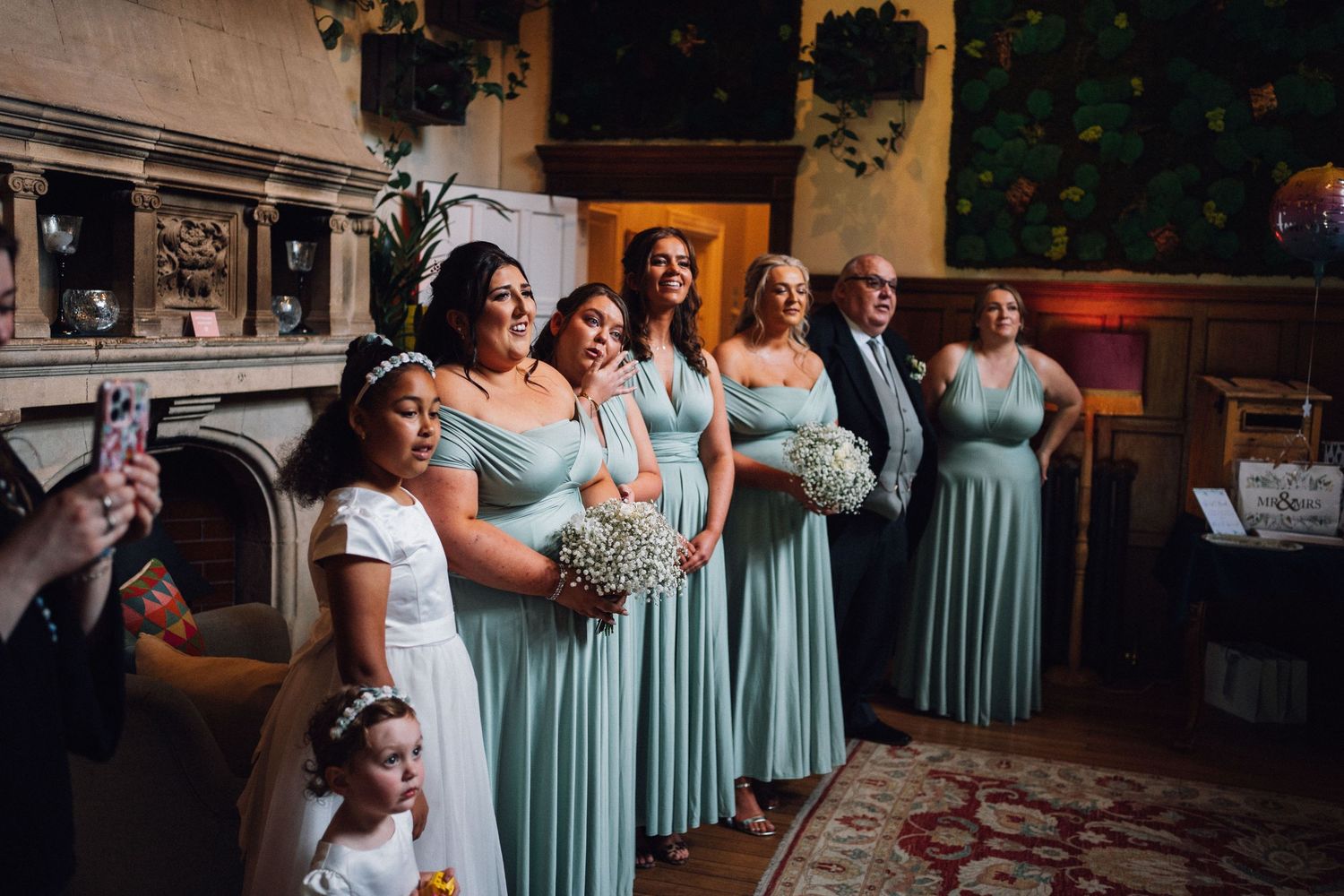 Bridesmaids in matching seafoam green dresses stand together at an elegant wedding ceremony.