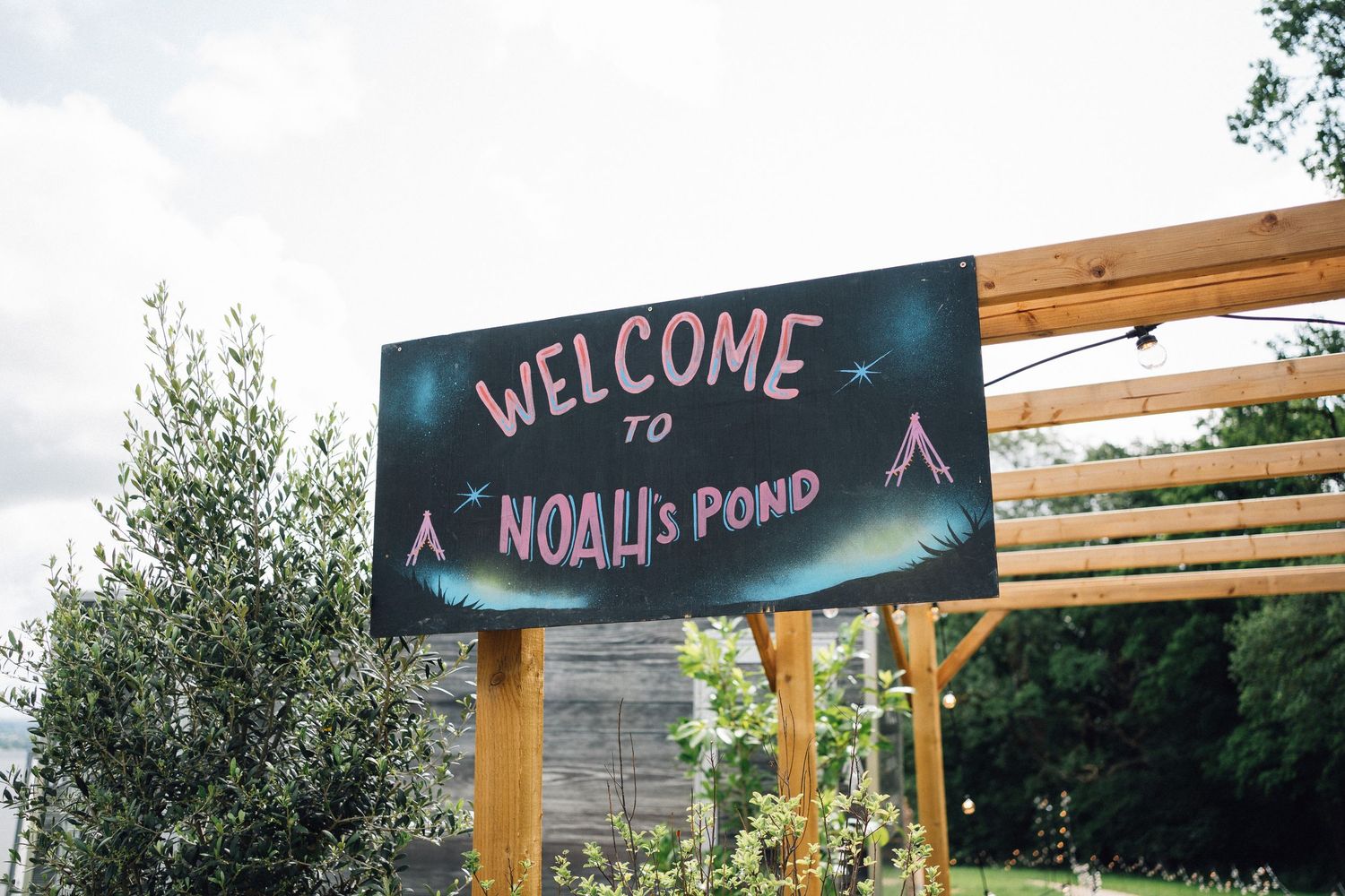 Rustic wooden welcome signs mounted on posts at an outdoor venue entrance.
