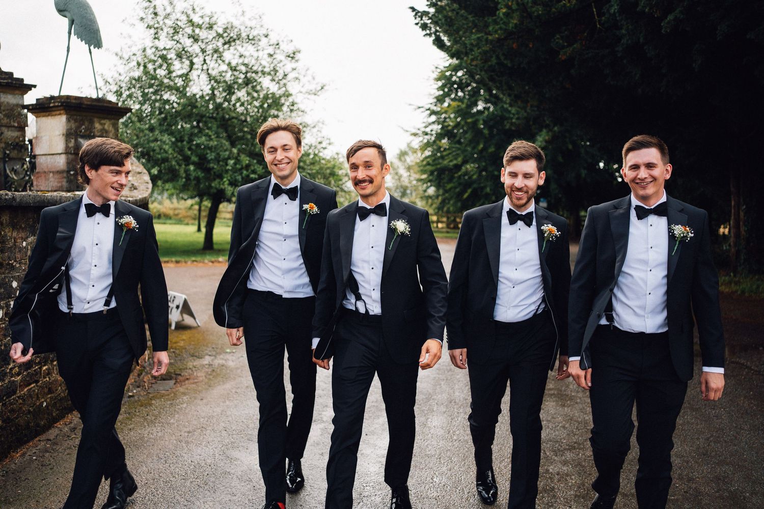 Group of men in formal attire posing together on a garden path.