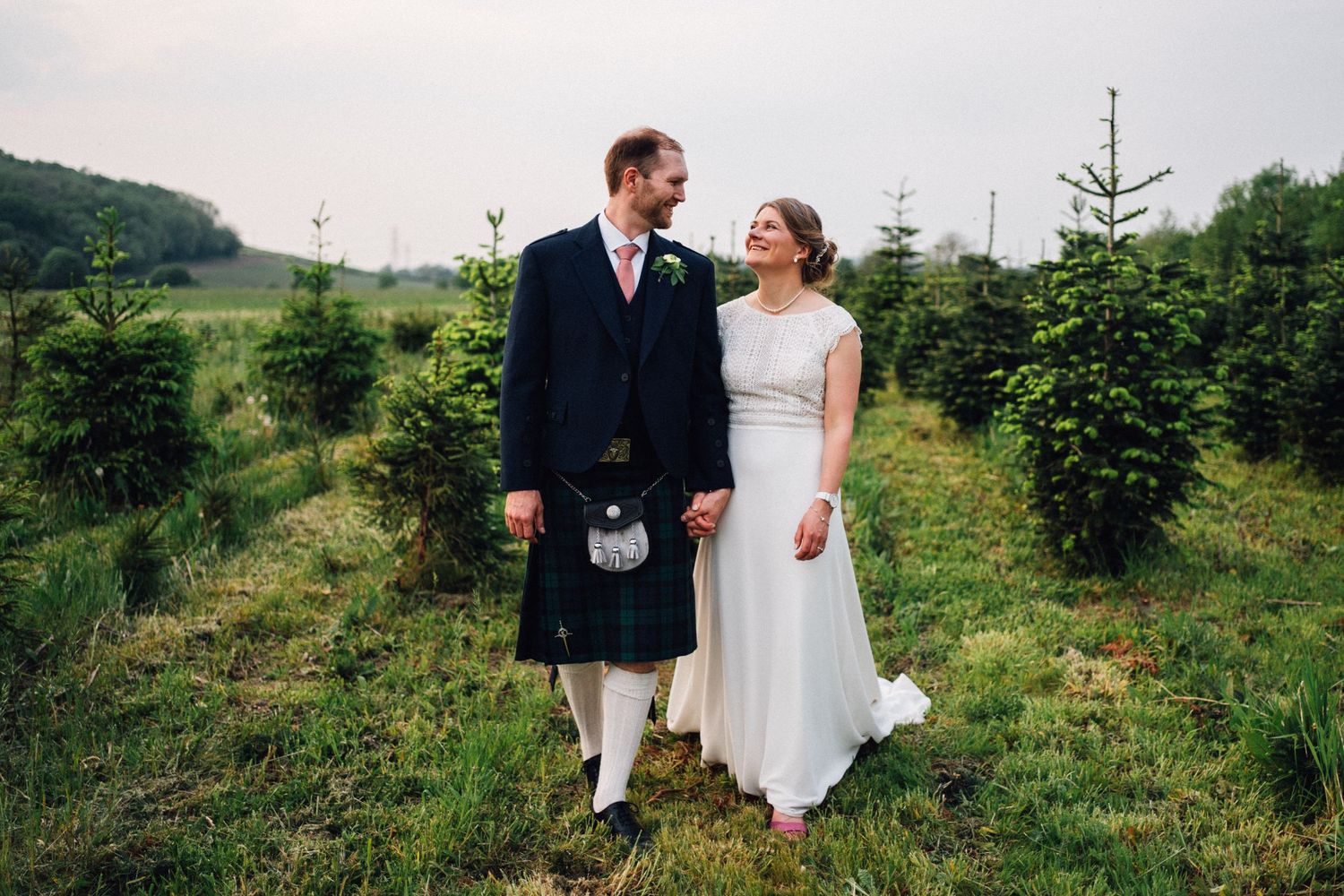 Wedding couple walking through a scenic evergreen tree farm on their special day.