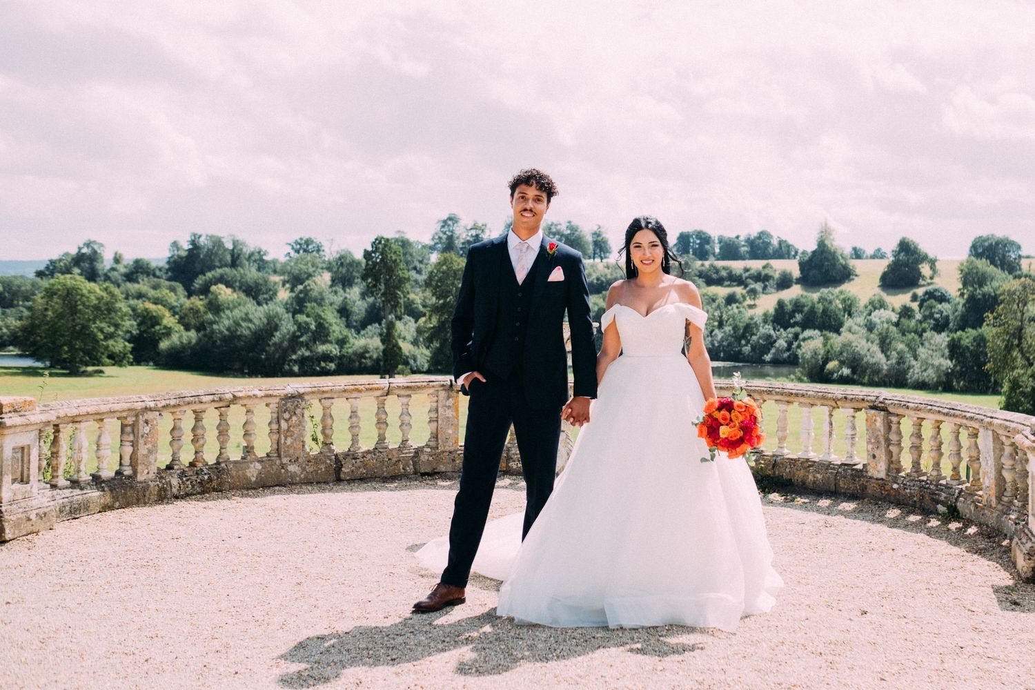 Wedding couple posing on stone terrace with scenic countryside views.