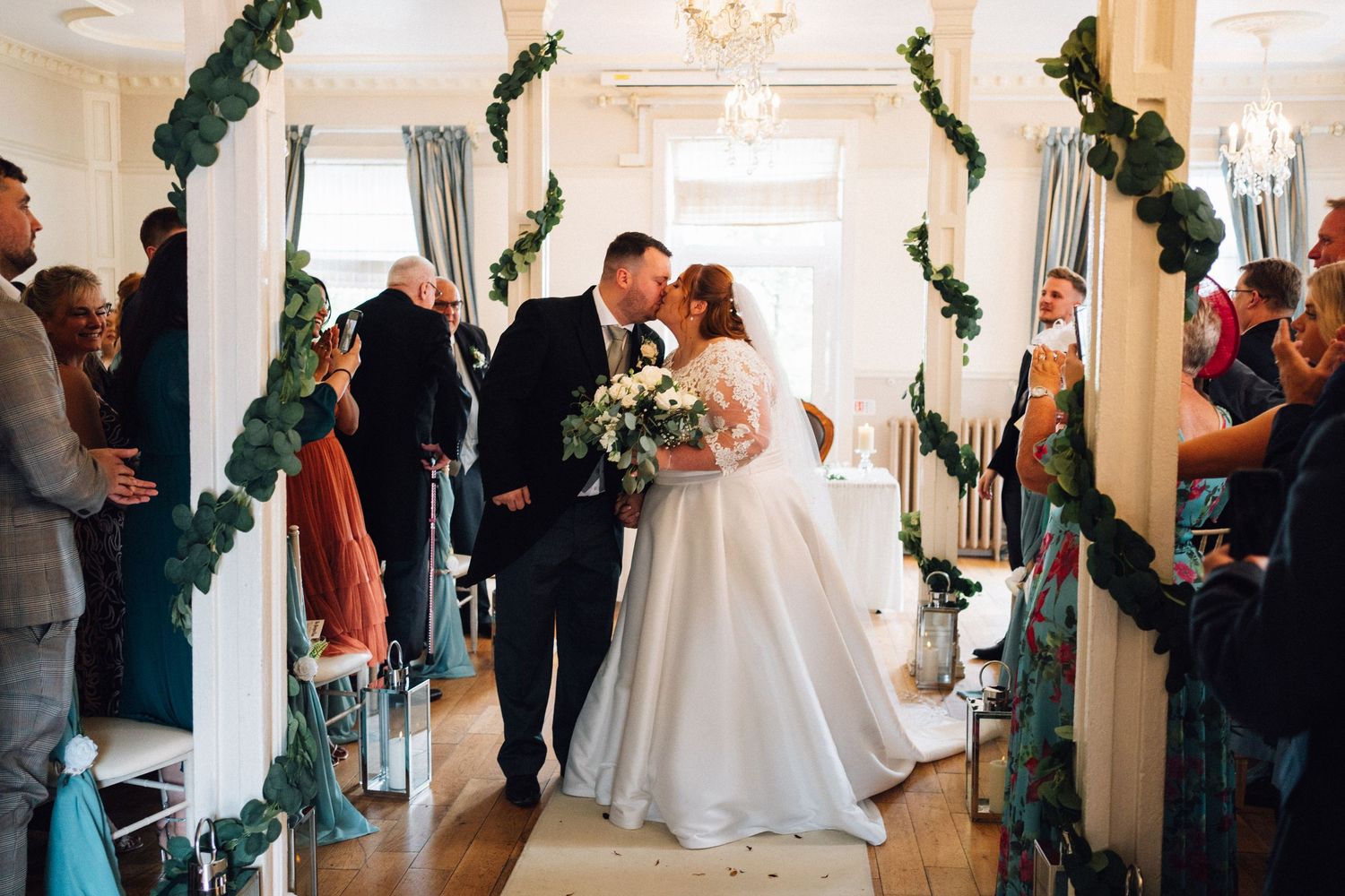 Indoor wedding reception with elegant white decor and floral garlands.
