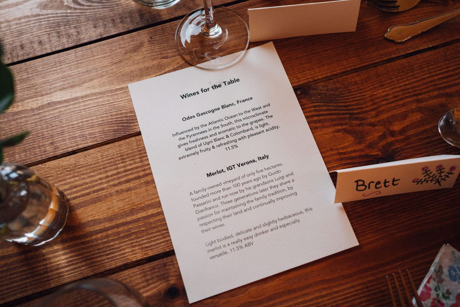 Wedding menu cards and place settings arranged on rustic wooden tables.