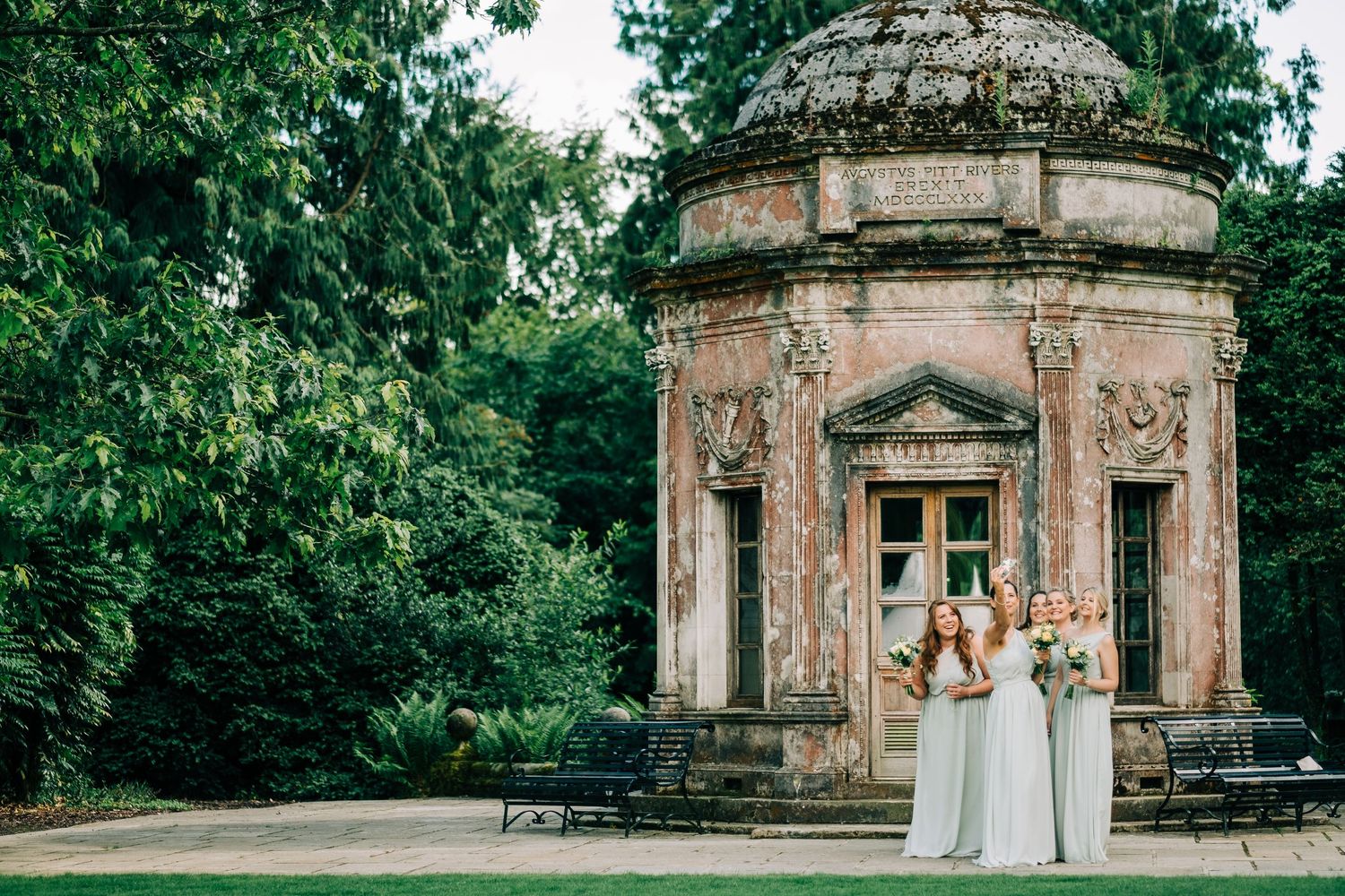 A classical stone gazebo structure in a garden setting.