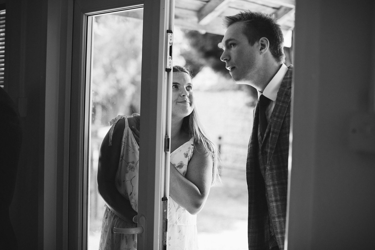 Monochrome image showing pre-wedding preparations through window reflections.