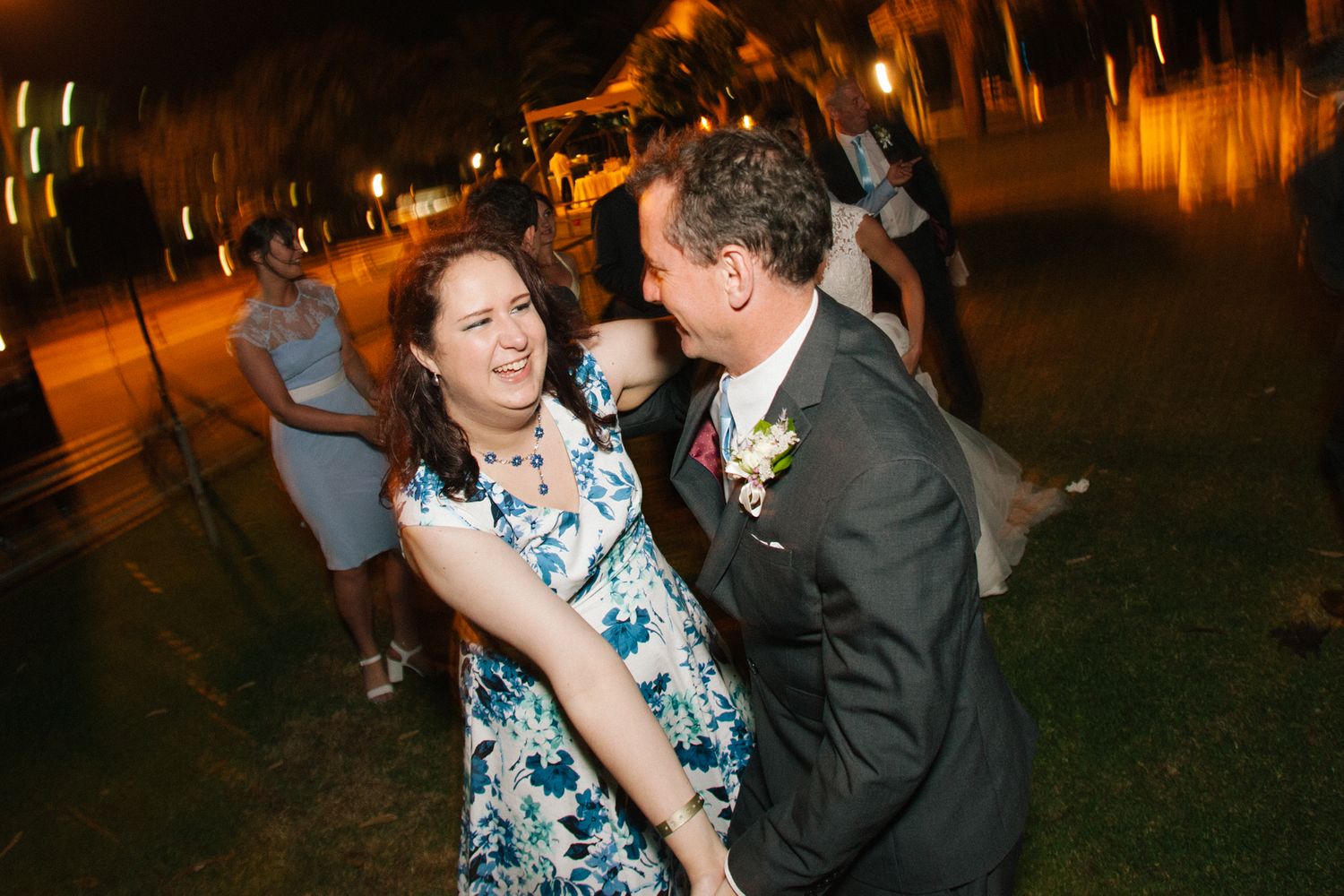 Wedding guests dance under warm lighting during an evening reception.