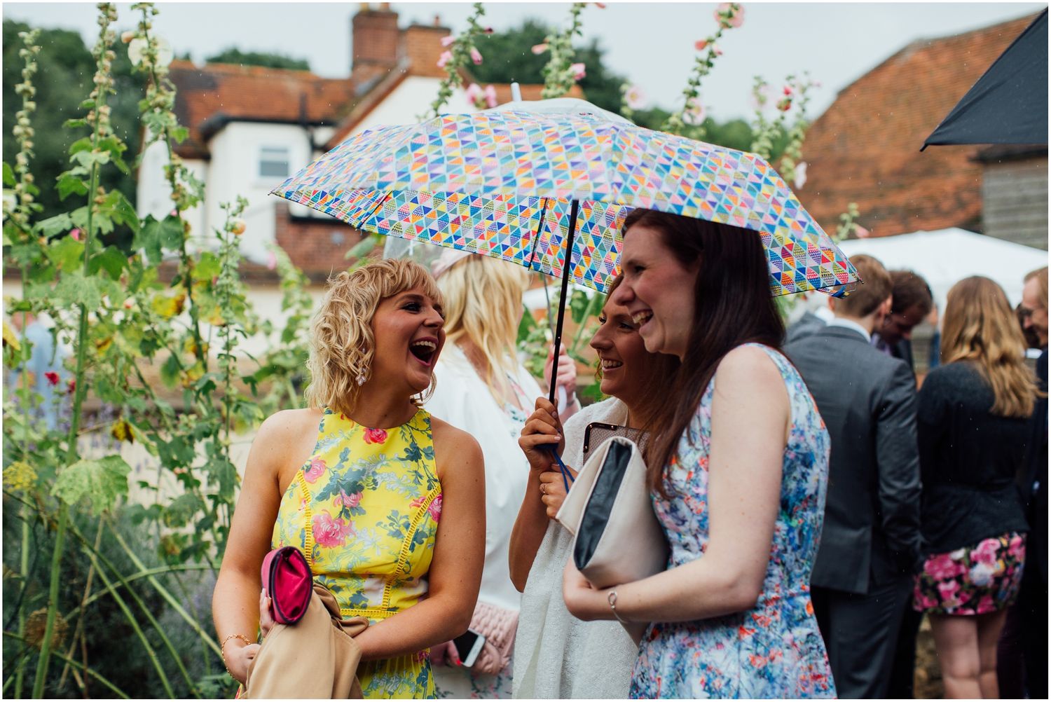 Wedding guests in colorful summer dresses socializing at an outdoor garden party.
