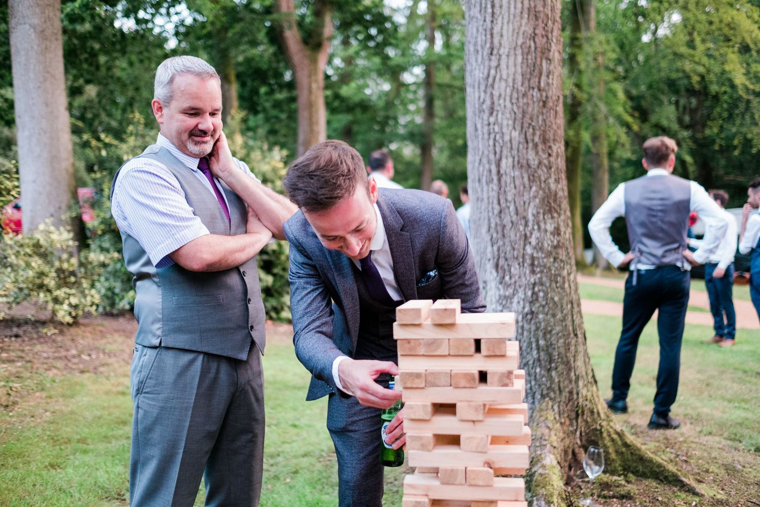 Wedding guests gather around a giant Jenga game during an outdoor reception.