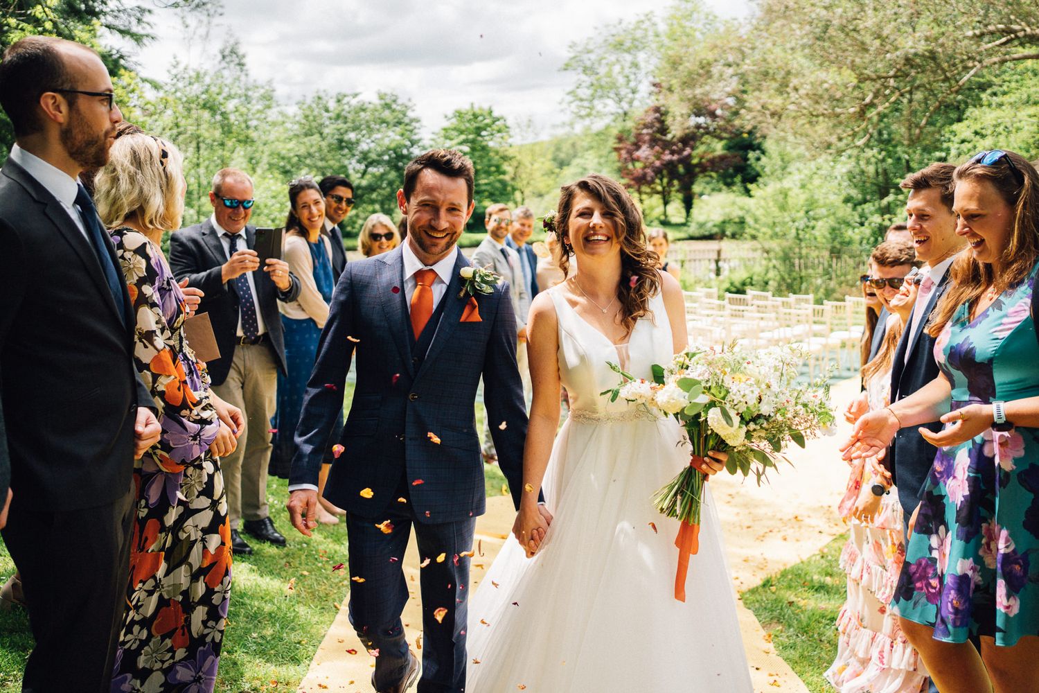 Wedding party walking and celebrating on a garden path surrounded by greenery.