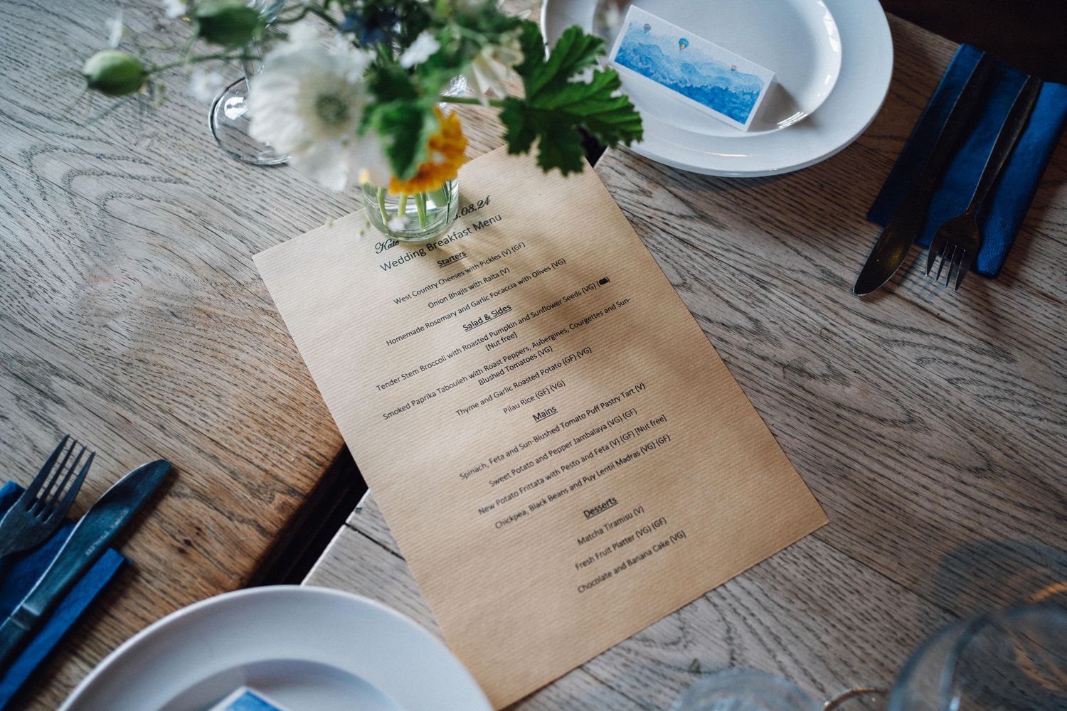 Wedding menu cards and place settings on rustic wooden tables.