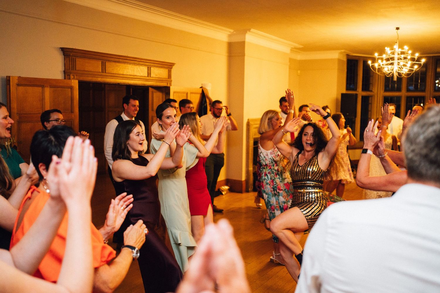 Wedding reception dance floor filled with guests celebrating under warm lighting.