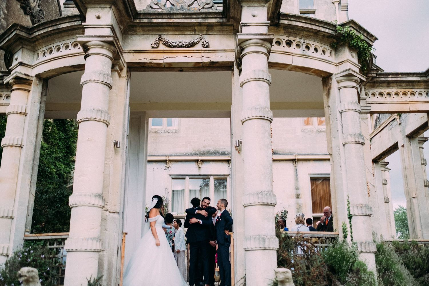 Wedding ceremony taking place under grand white classical columns of a historic building.