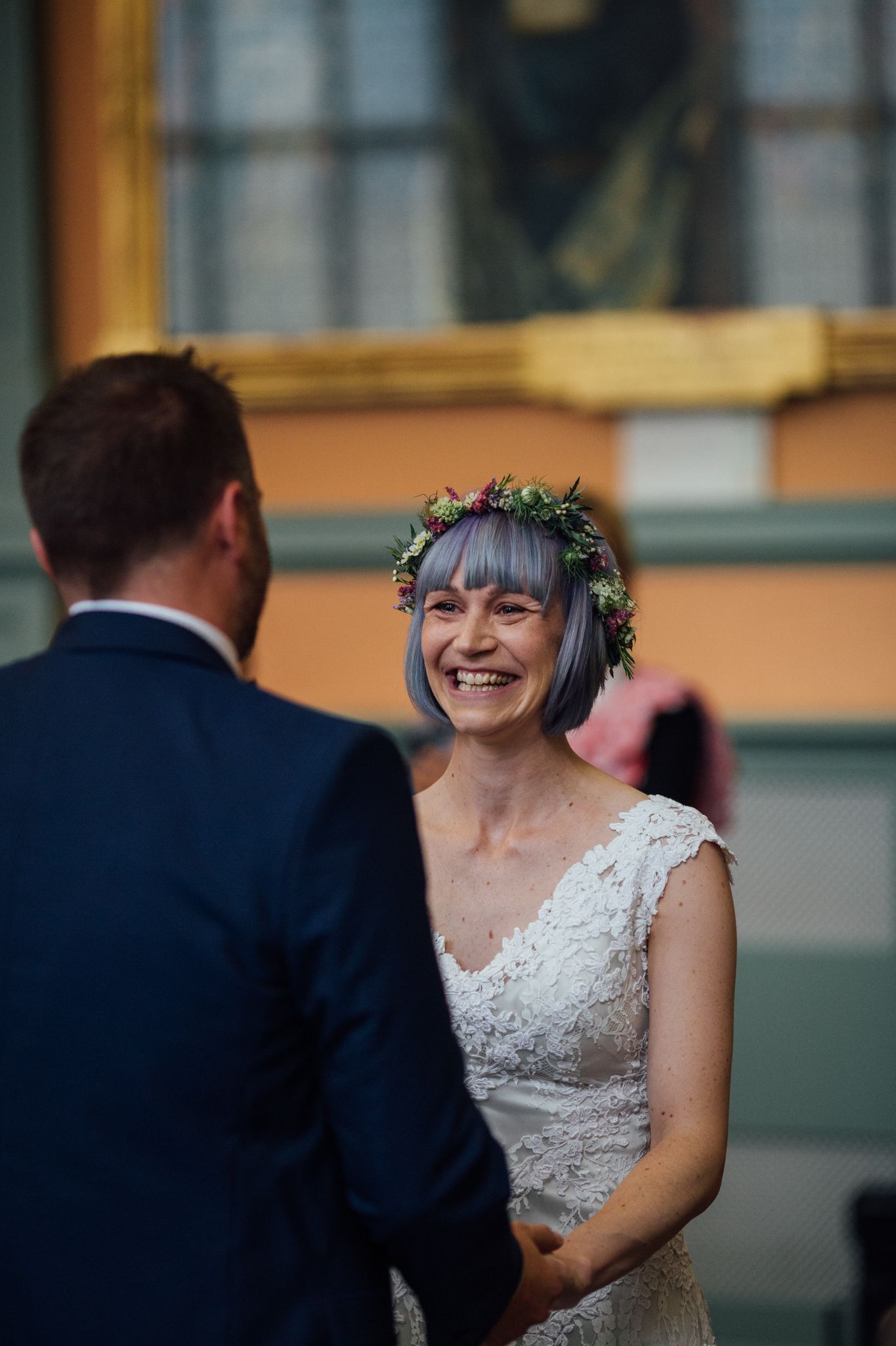 A joyful moment captured during a wedding ceremony with a bride wearing glasses and a floral crown.
