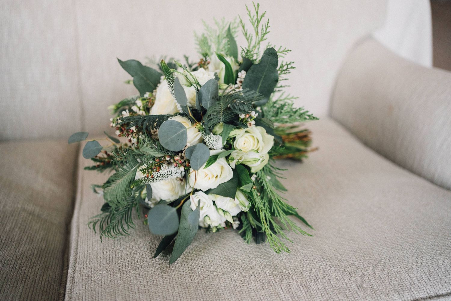 Elegant white and green floral arrangements with eucalyptus displayed on wooden surfaces.