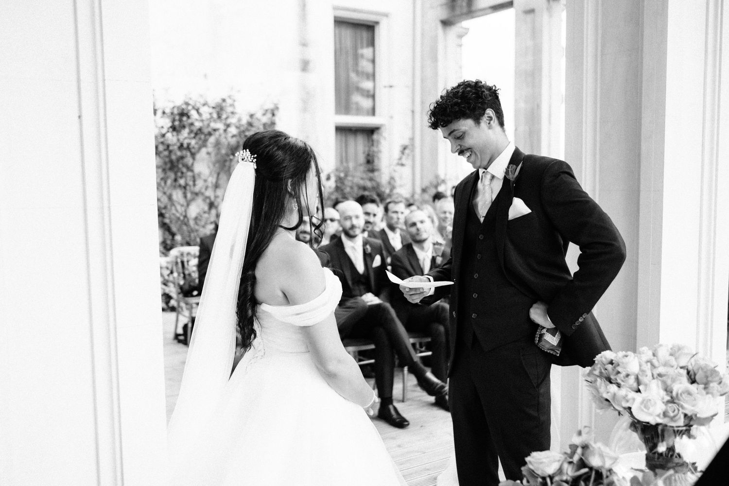 Black and white wedding photo capturing a candid moment during the ceremony exchange.