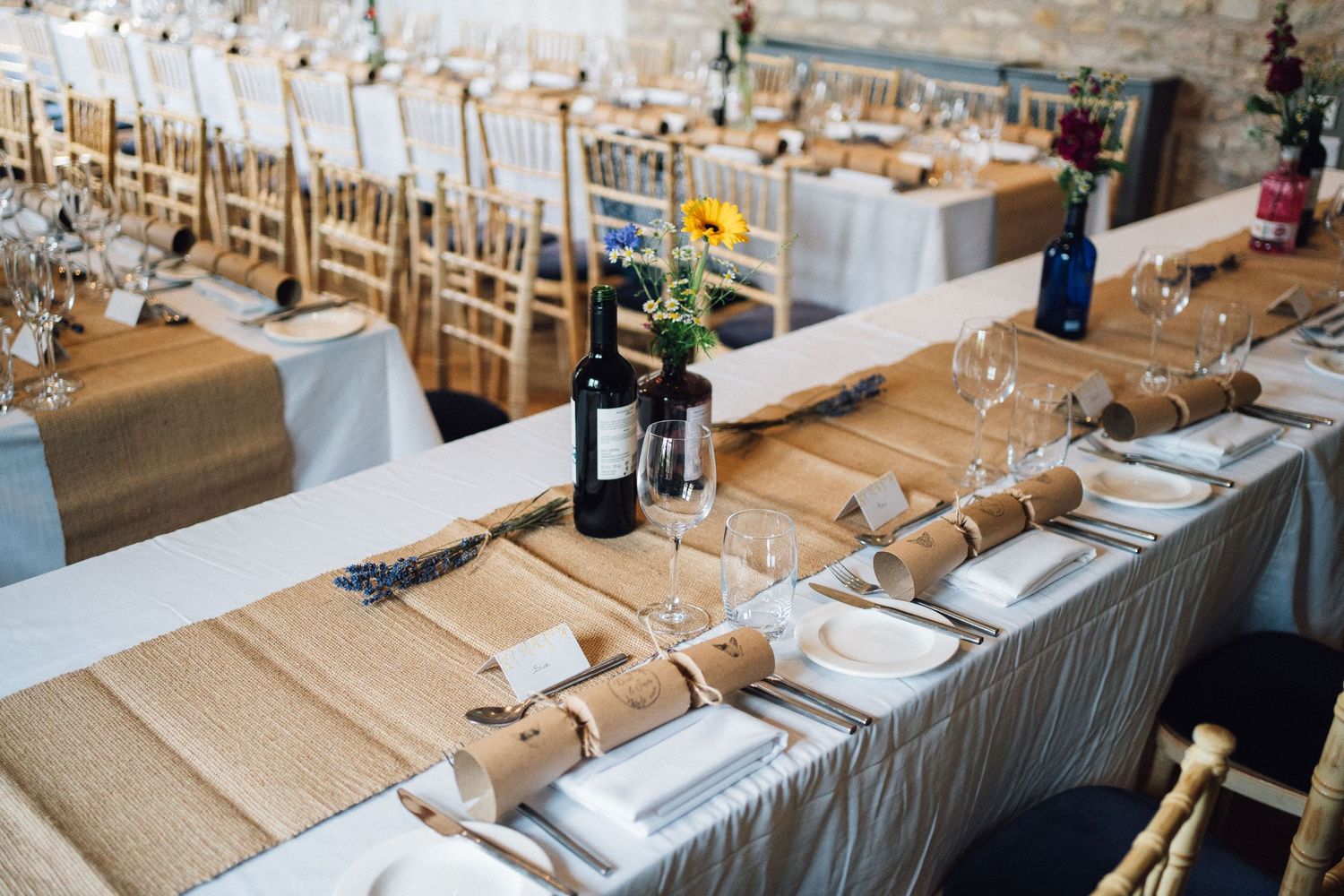 Elegant wedding reception table setting with burlap runners and chiavari chairs.