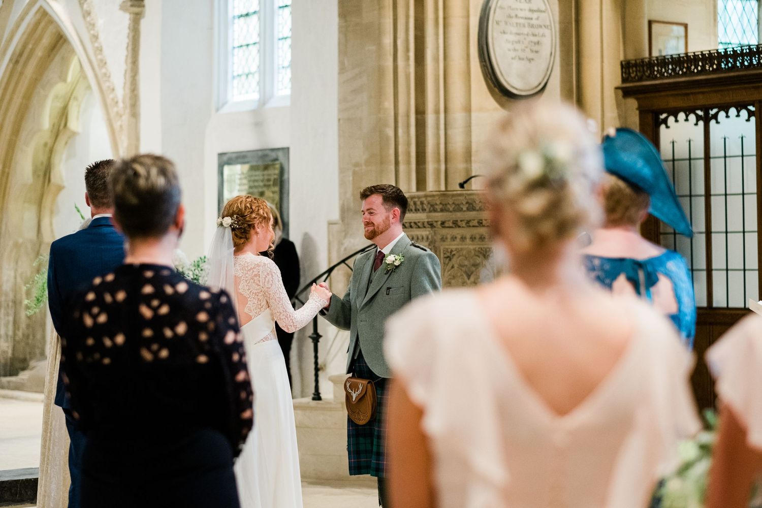 Wedding ceremony gathering inside historic stone church with vaulted ceilings.