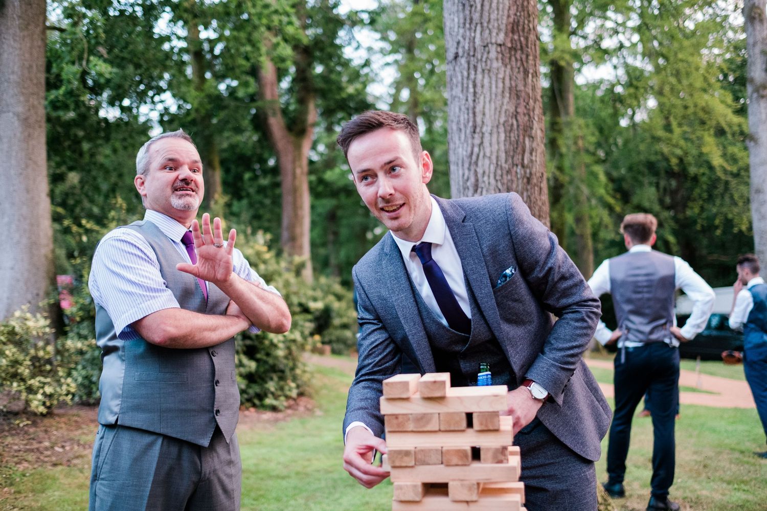 Group of guests playing giant Jenga on a wooden table during an outdoor wedding reception.