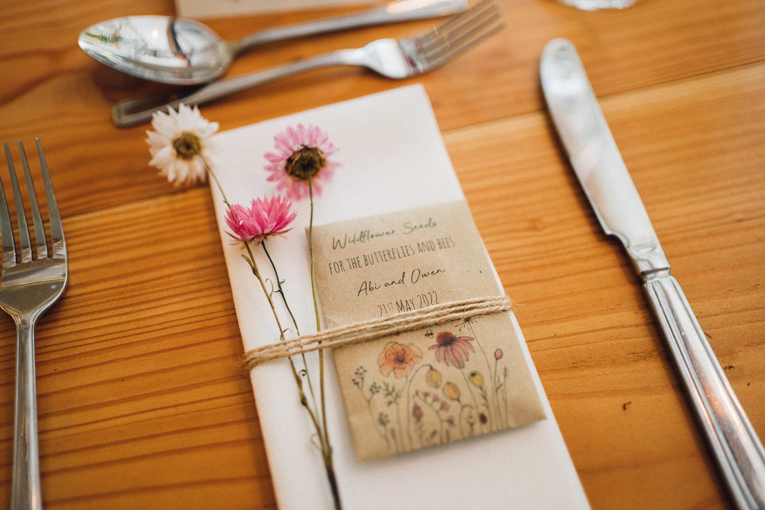 Close-up of elegant wedding place settings with pink flowers and kraft paper details.