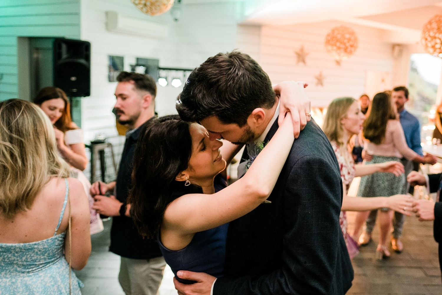 Wedding reception dance floor with couples dancing in romantic lighting.