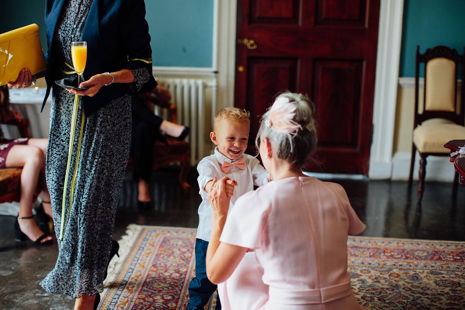 Young child in formal attire enjoying refreshments at indoor event.