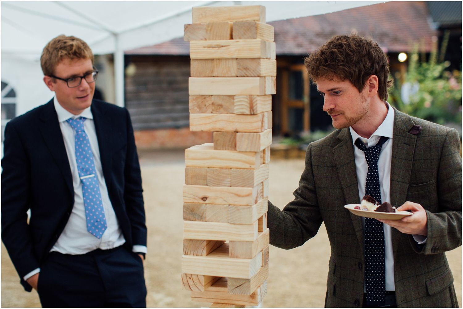 Group playing giant Jenga game at outdoor event with wooden blocks stacked high.