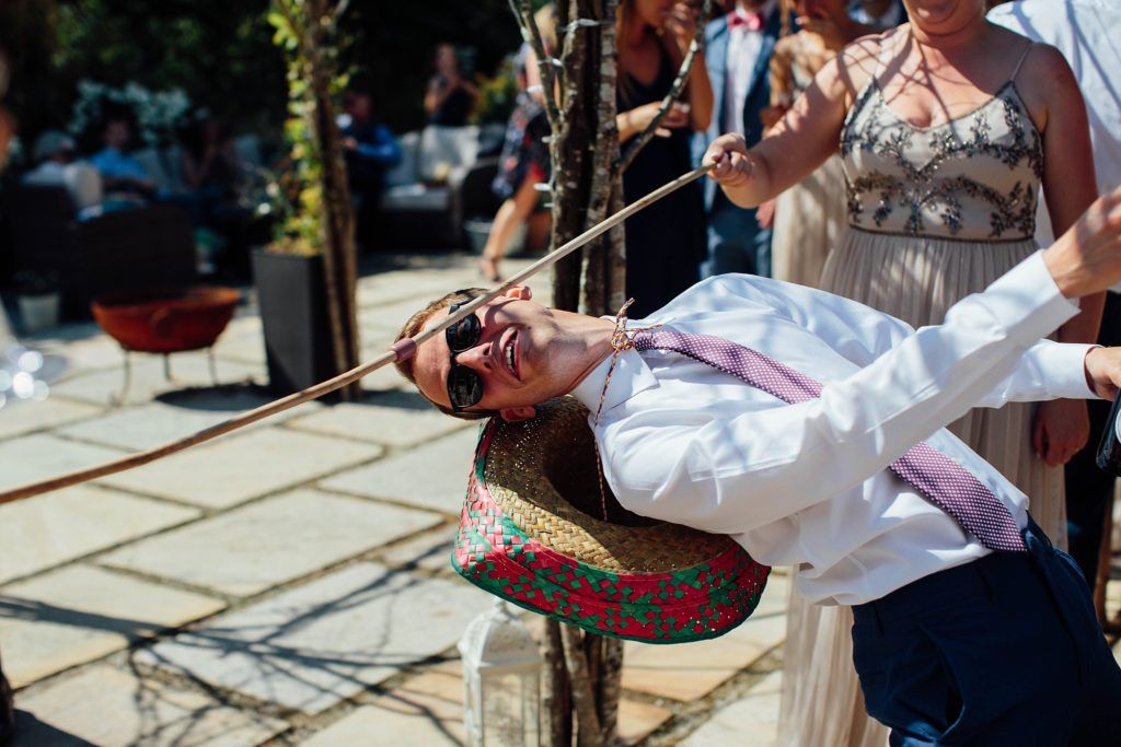 A person in white clothing swings playfully on ropes at an outdoor celebration.