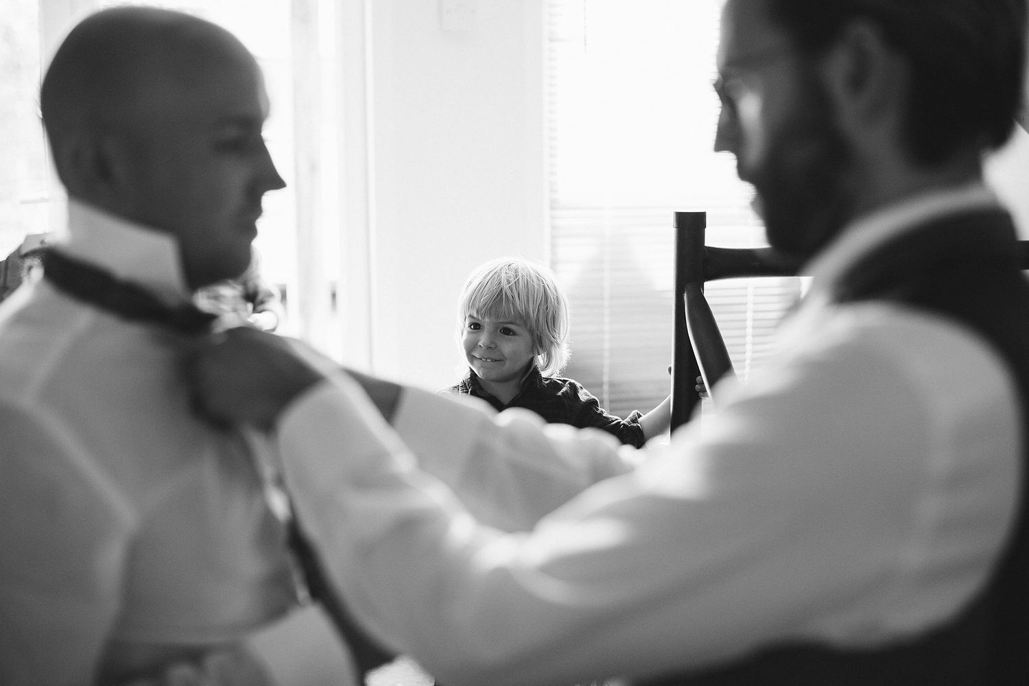 Black and white photo capturing candid moments of wedding party preparations.