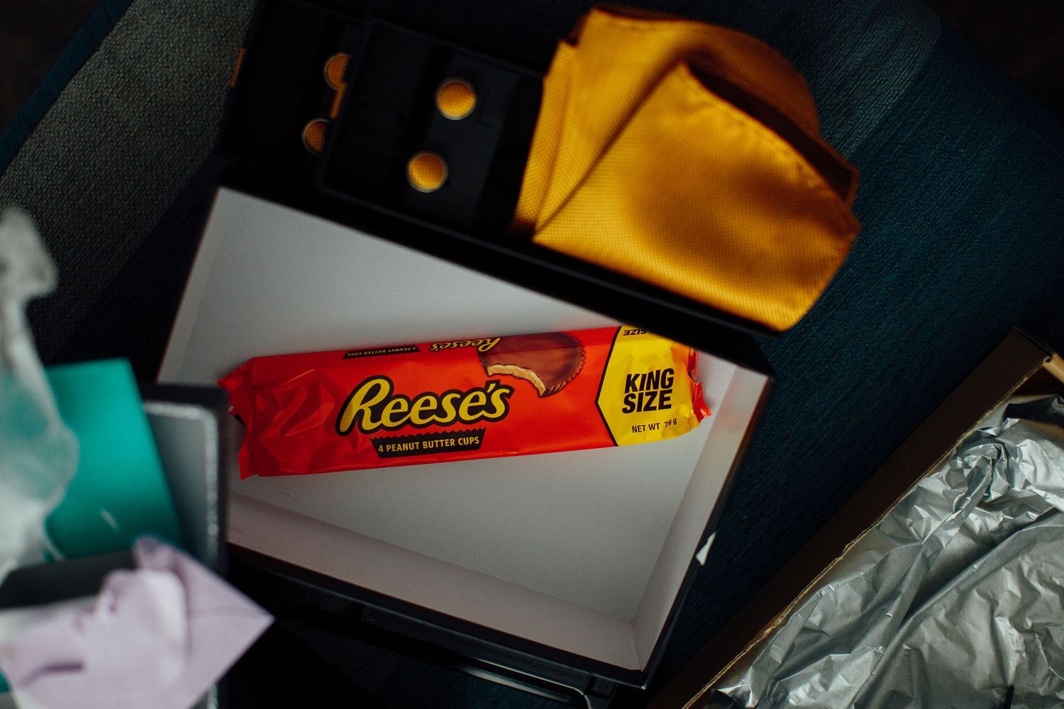A Reese's candy bar package with a yellow napkin in dark lighting.