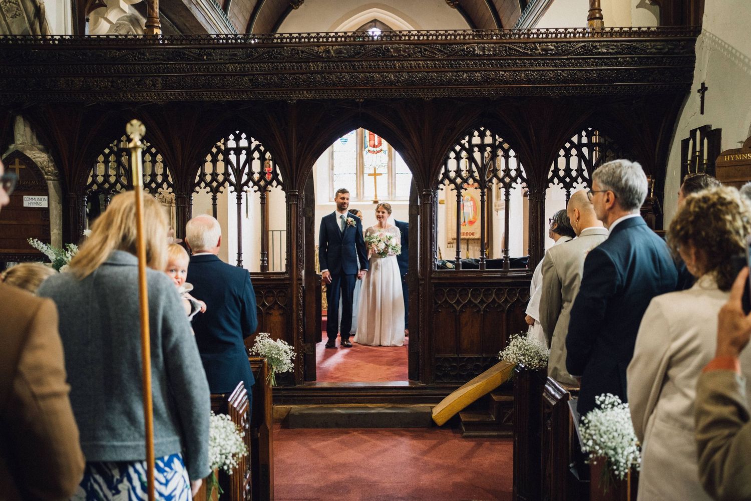 Church wedding ceremony with elegant floral arrangements and wooden gothic details.