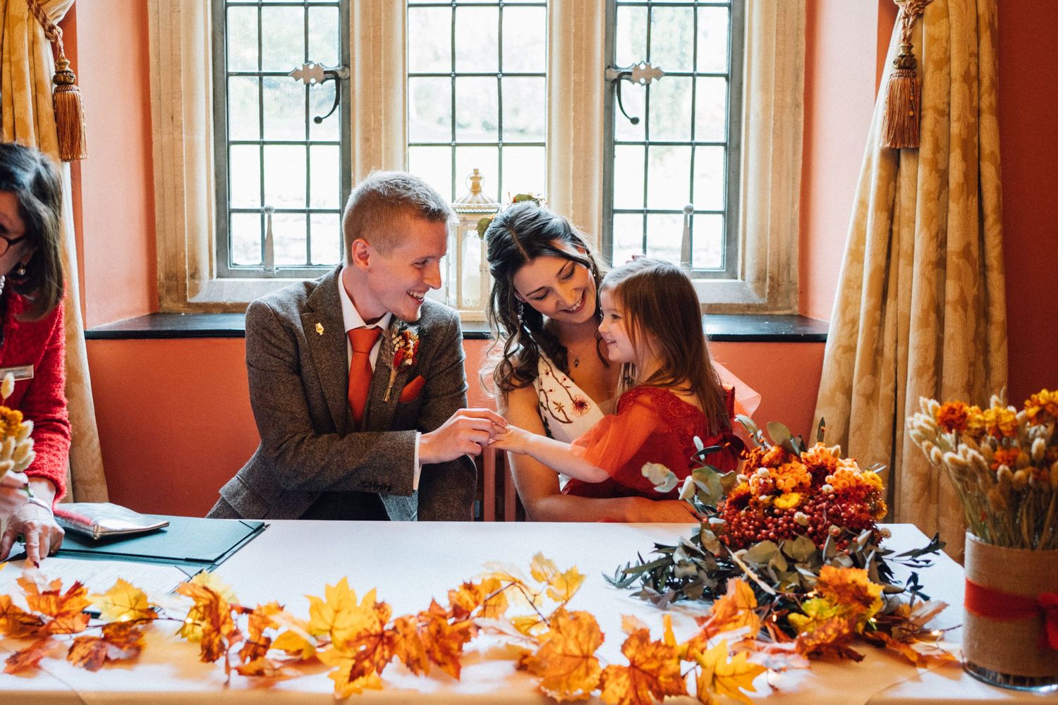 A festive autumn dining table decorated with orange fall leaves and pumpkins as guests gather for a holiday meal.