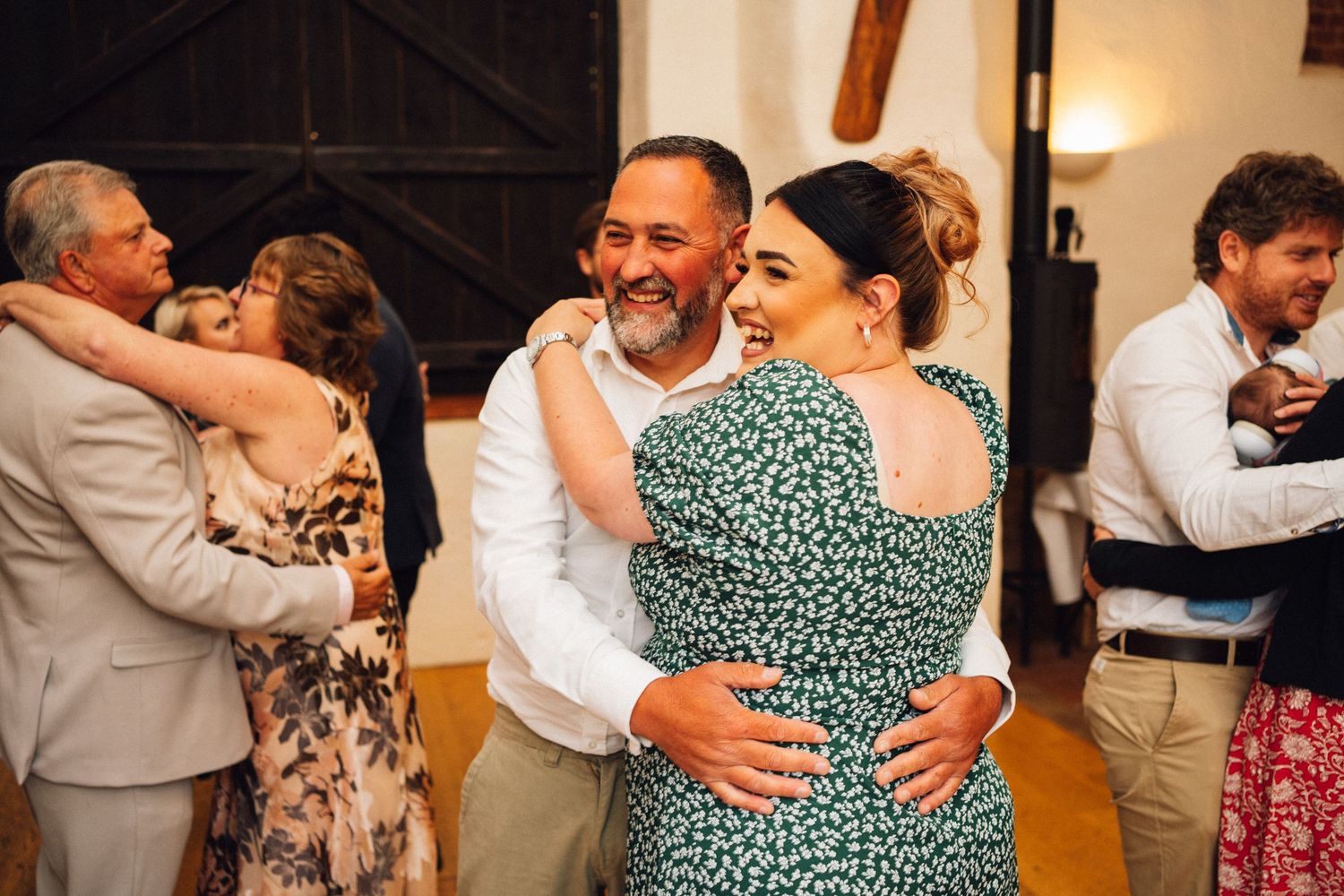 People dancing together at a wedding reception in a warm-lit indoor venue.