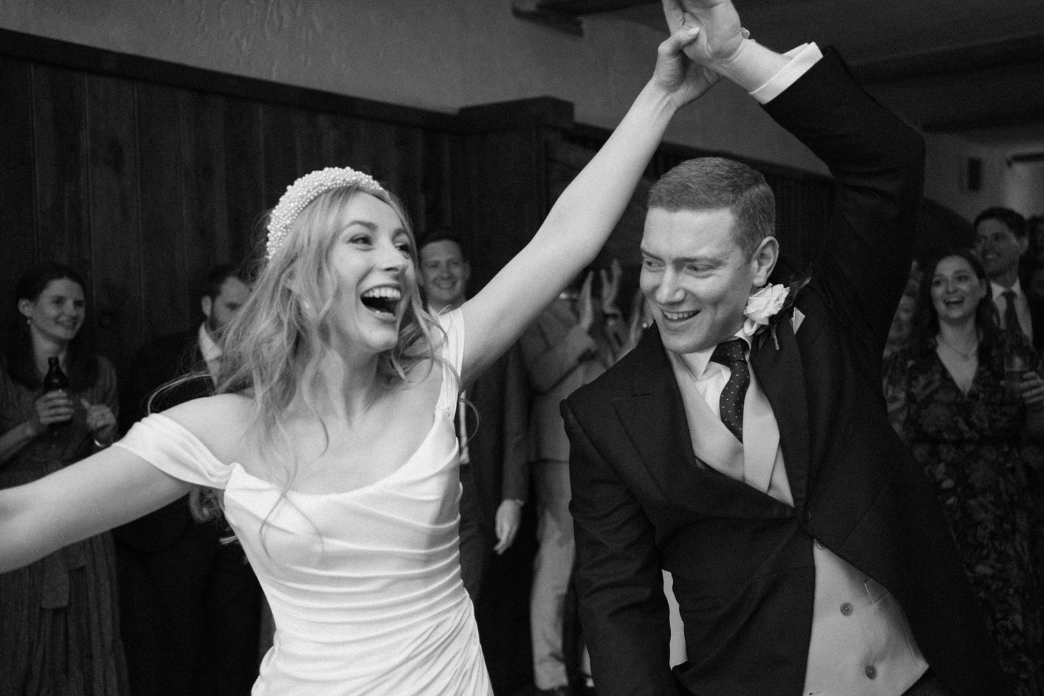 People dancing and celebrating at a wedding reception in black and white.
