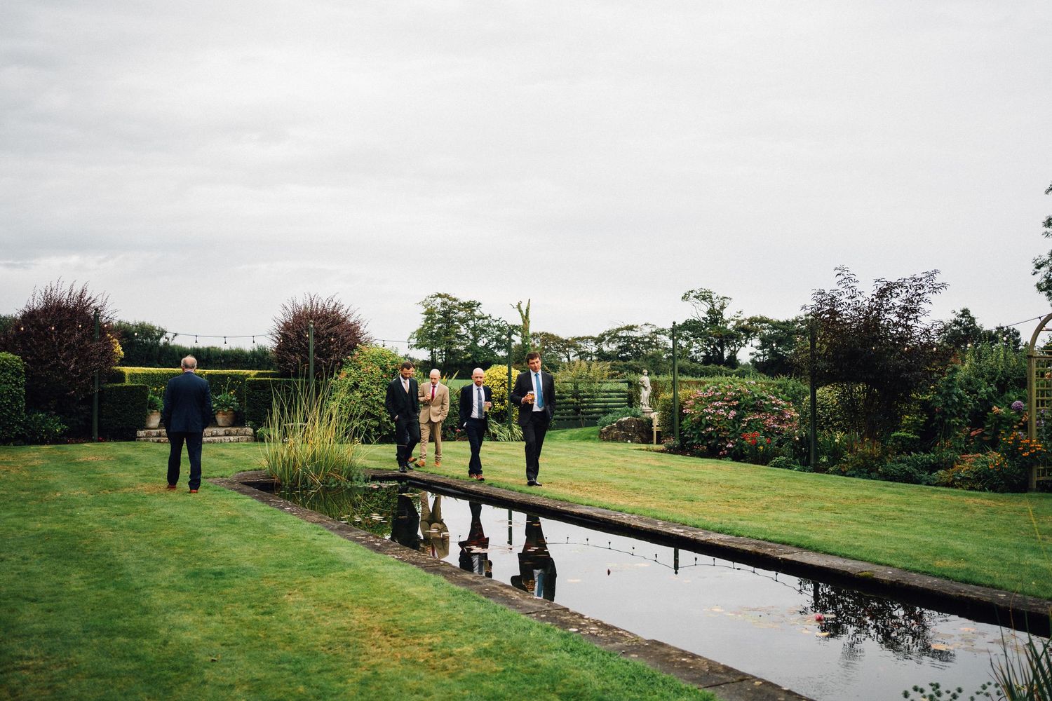 Scenic outdoor wedding venue with reflecting pool and green landscaping surrounded by trees.