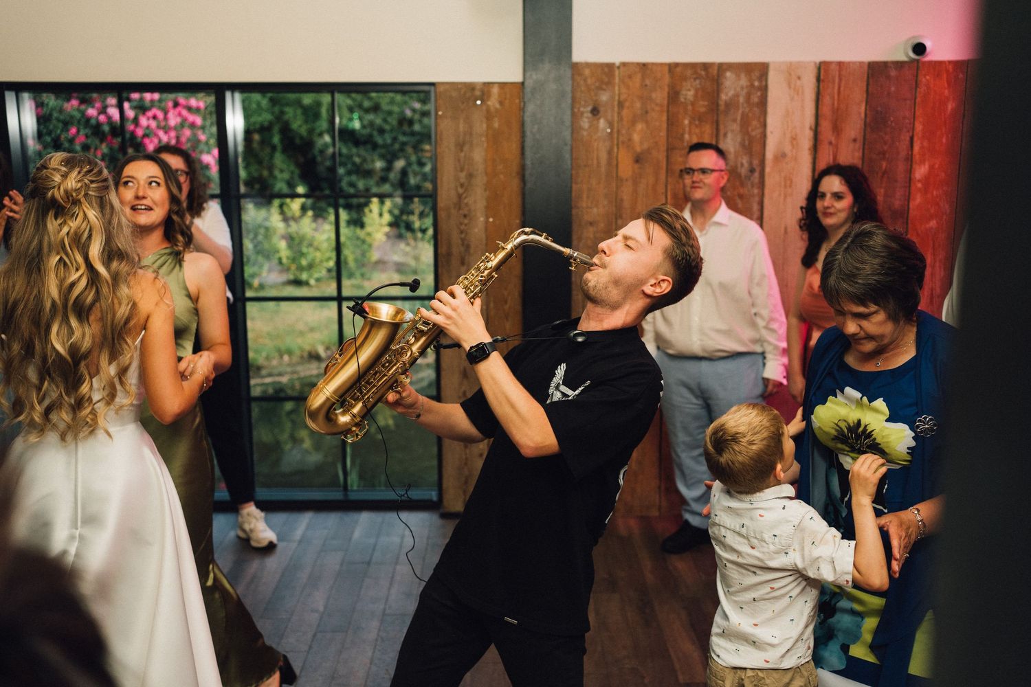 Wedding party dancing and celebrating in a rustic venue with natural lighting.