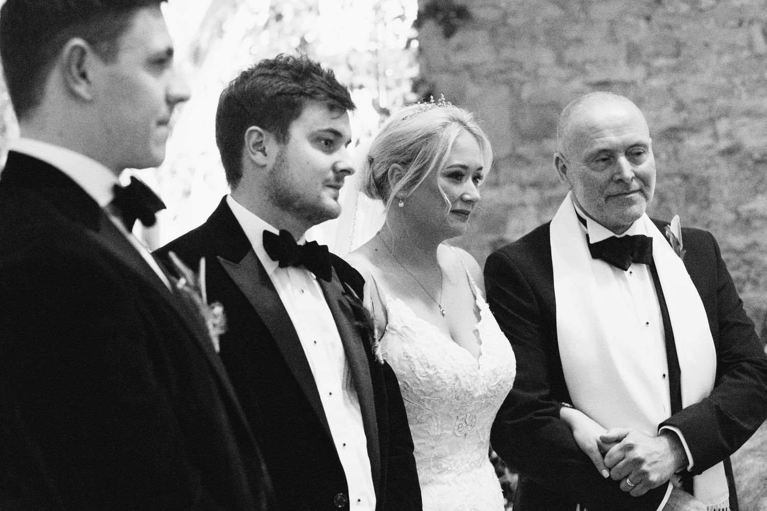 Formal wedding party members sharing candid moments in stone venue.