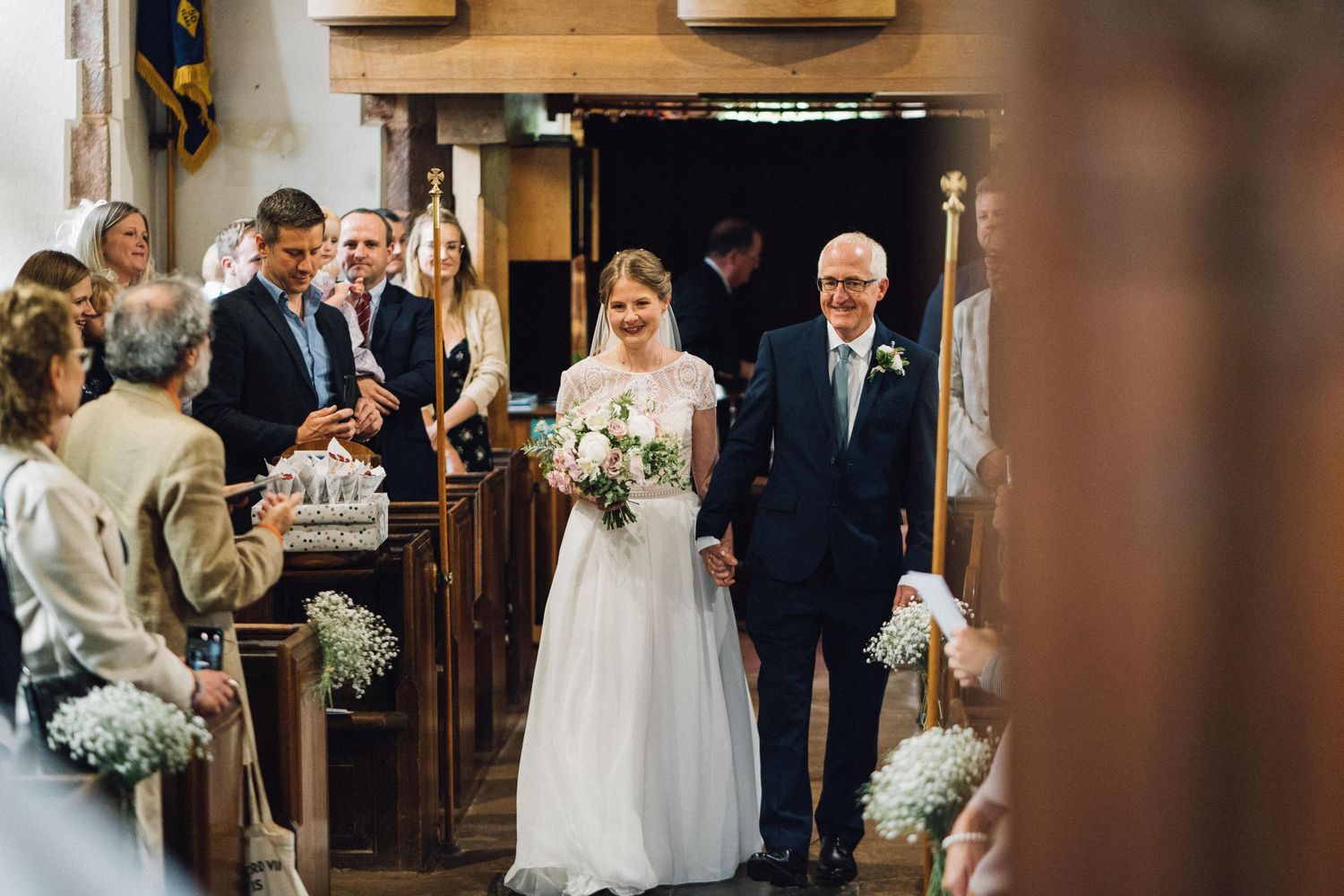 Wedding ceremony proceedings inside historic church with wooden details.