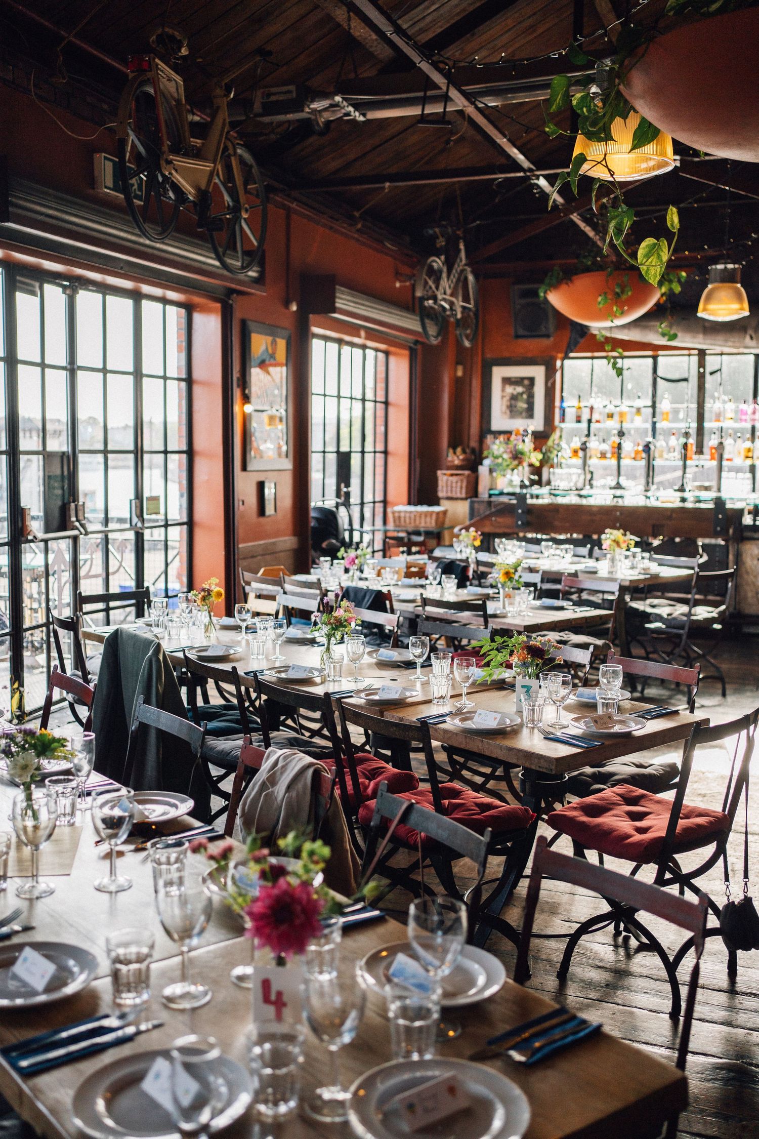 Spacious restaurant interior with wooden tables and large windows providing natural light.